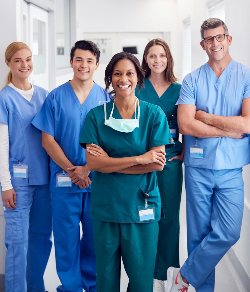 Portrait Of Smiling Multi-Cultural Medical Team Standing In Hospital Corridor